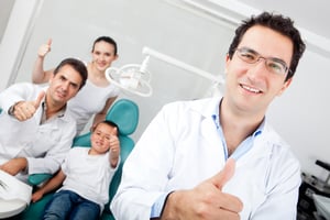 Friendly male dentist and team with thumbs up